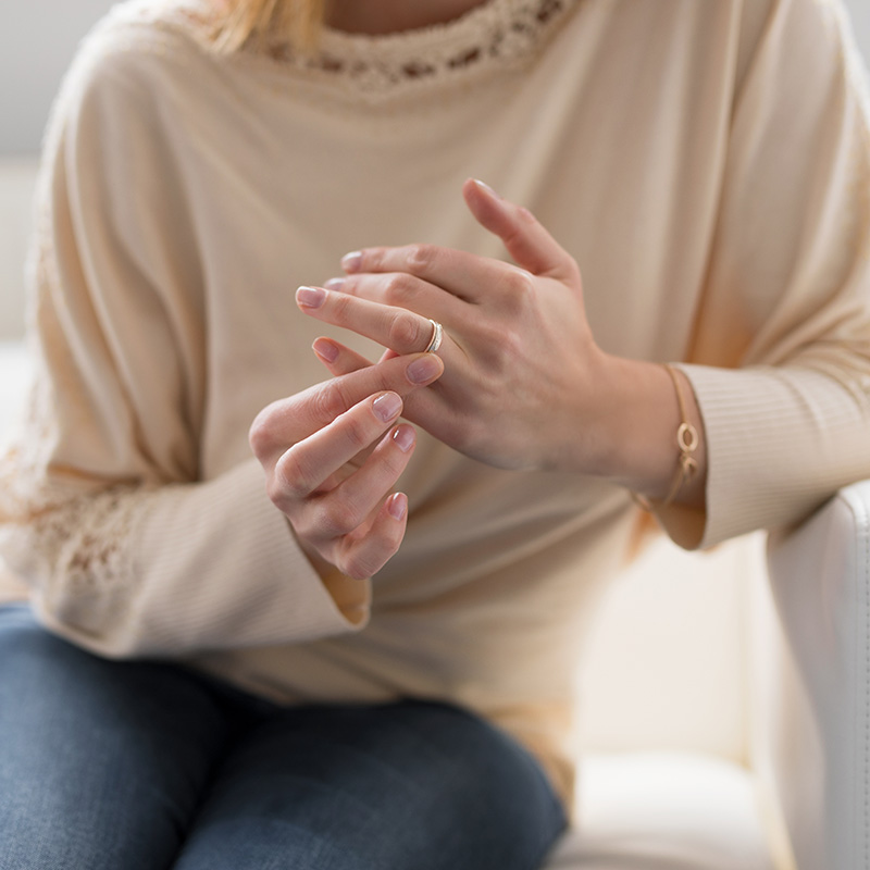 Woman holding her wedding ring, unsure about staying in her relationship. Discernement counseling in NY